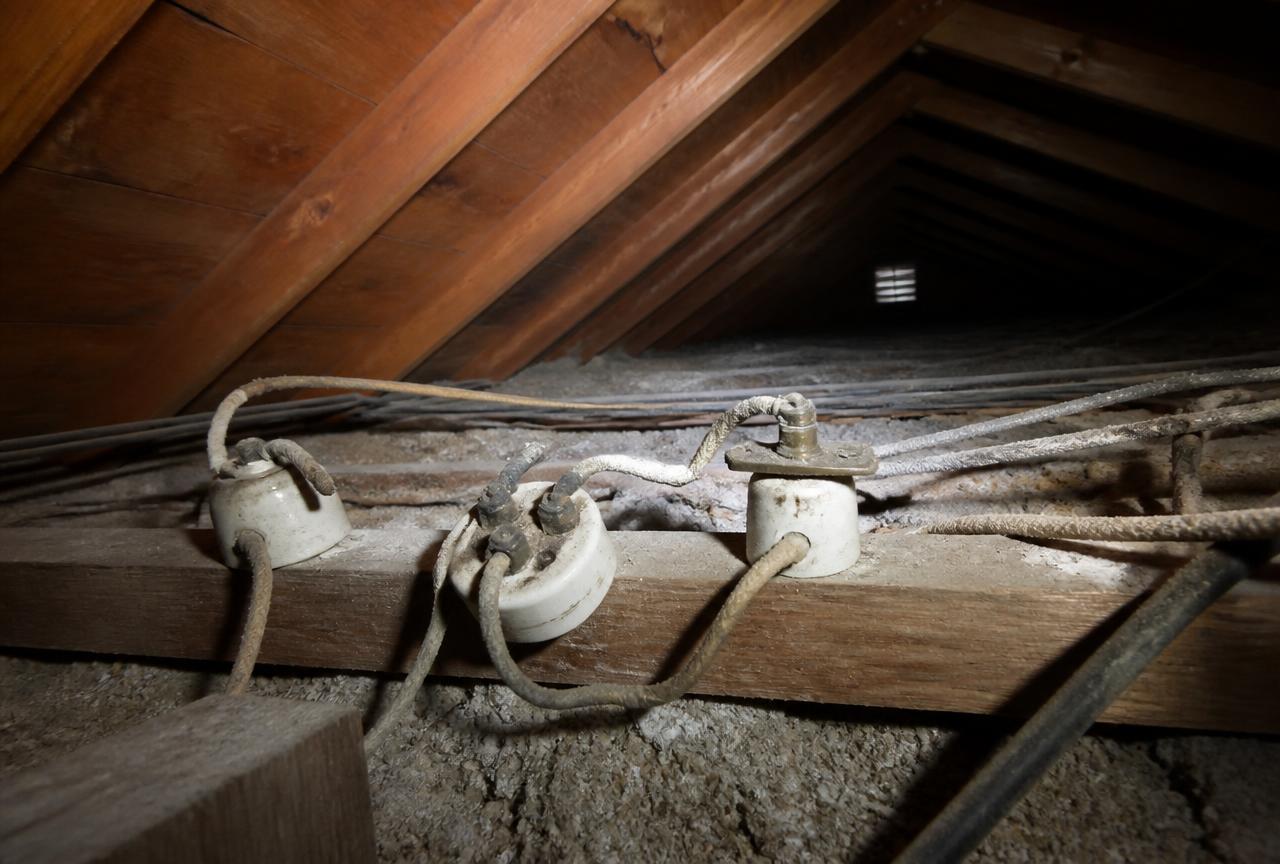 Cloth-insulated knob and tube wiring running across rafters in a residential attic
